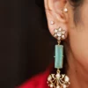 Close-up of woman wearing gold-plated Mehfil Earrings with green stone and kundan floral design by Twilight by Twinkle