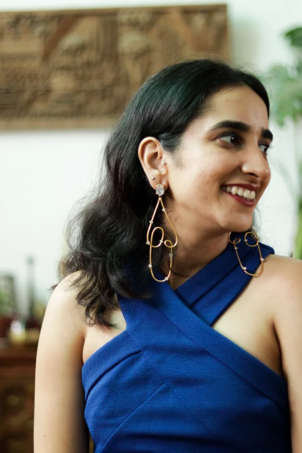 Abstract sculptural gold earrings with delicate crystal details on model