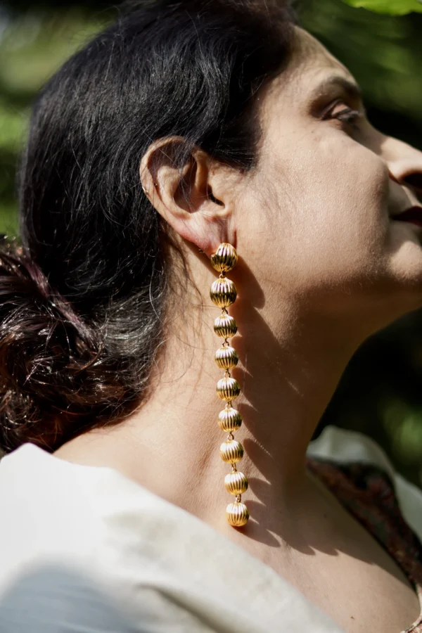 Model wearing long sculptural gold statement earrings with dome shapes by Twilight by Twinkle